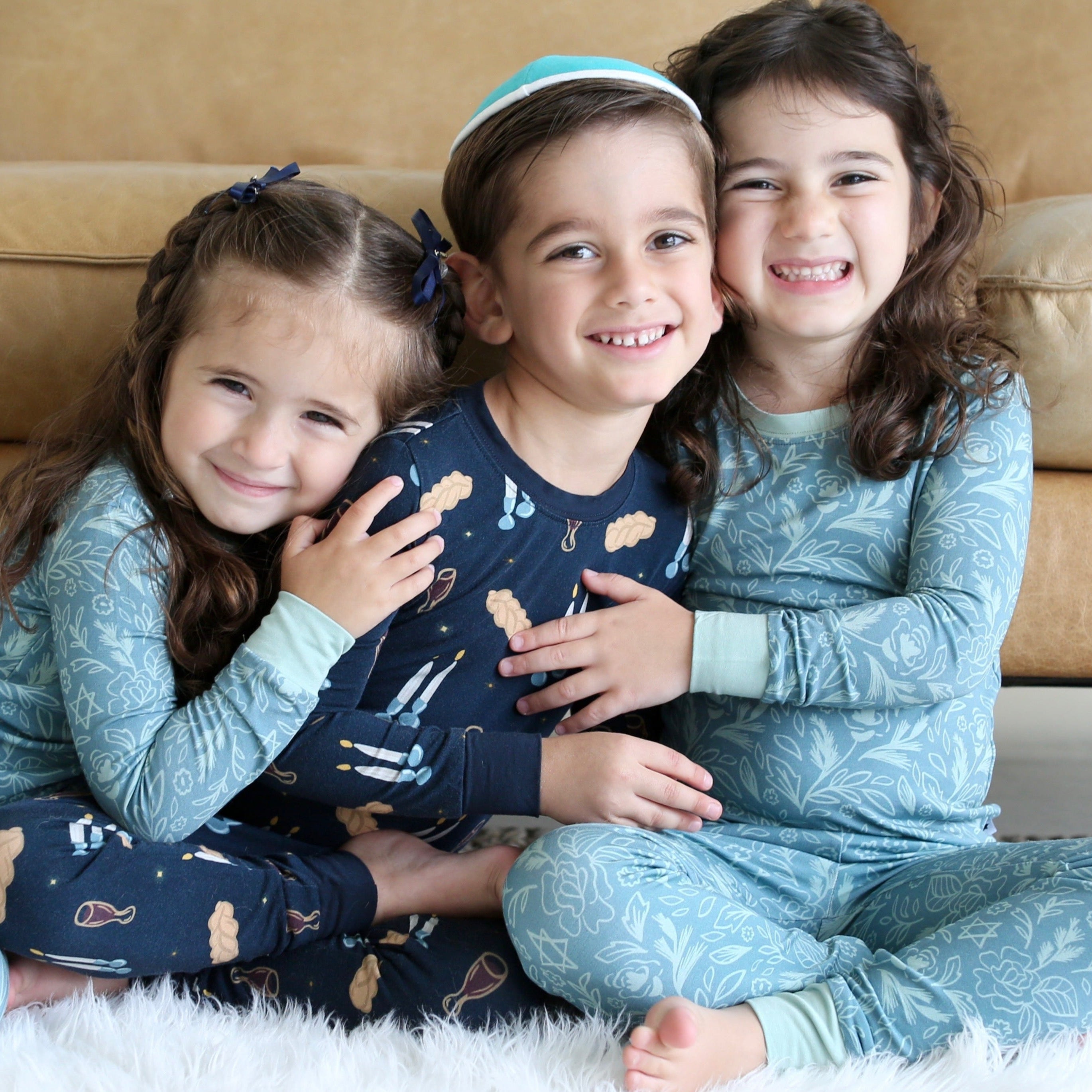 Three children in pajamas sitting together on a couch