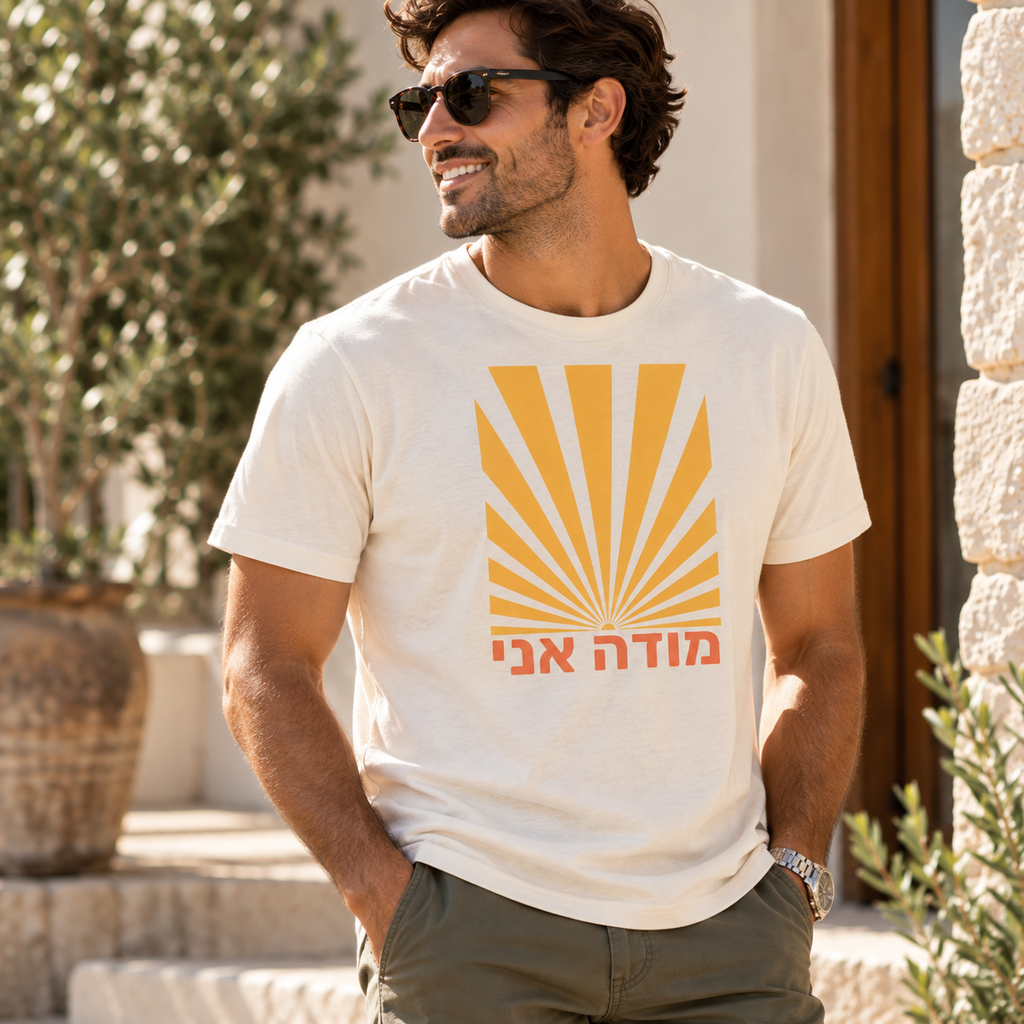 Man wearing the vintage white Modeh Ani Hebrew T-shirt by Poppy Lane with a retro sunrise graphic.
