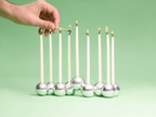 Hand lighting a candle in the Polished Aluminum Bubble Menorah by Tchotchke