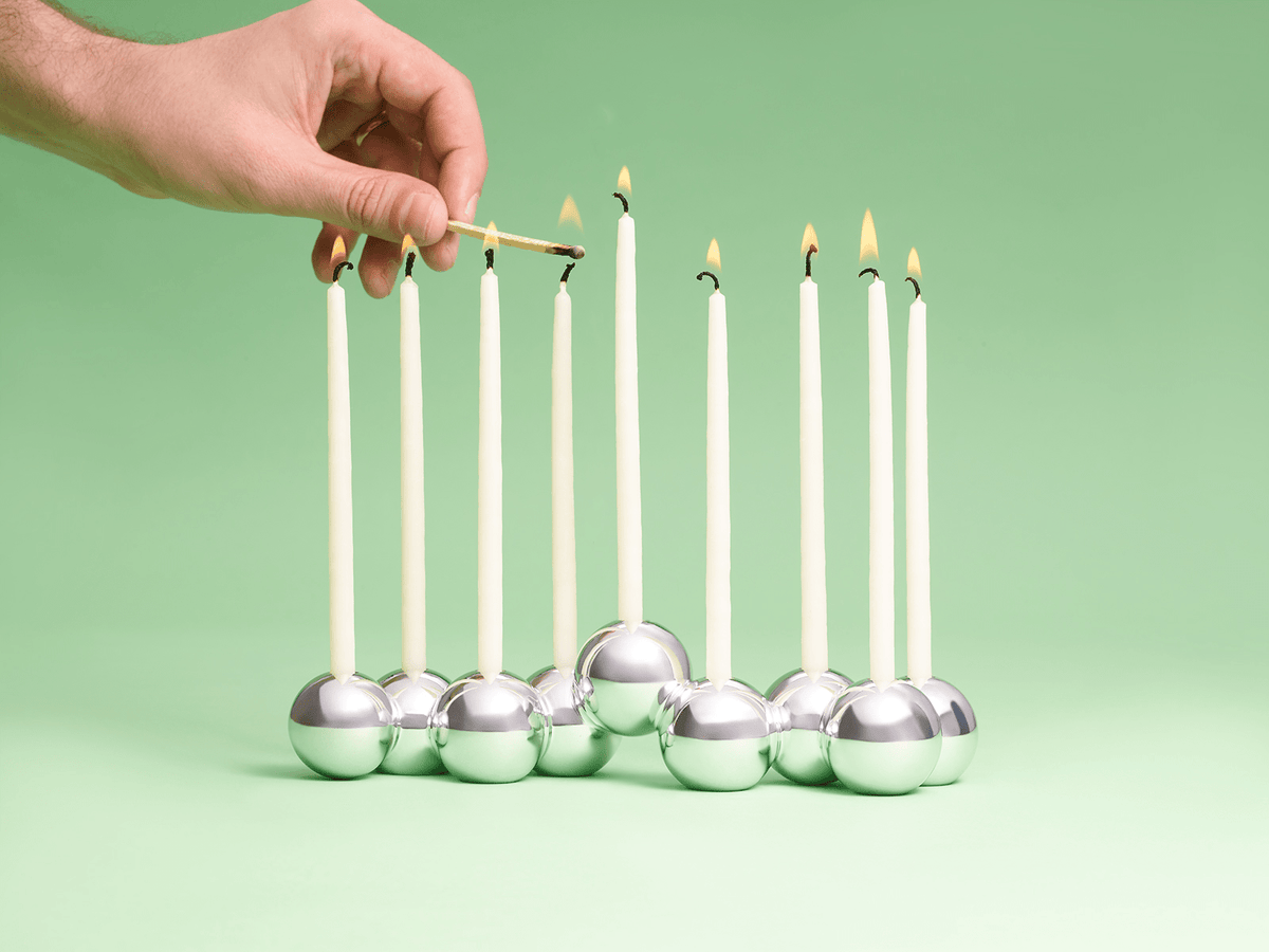Hand lighting a candle in the Polished Aluminum Bubble Menorah by Tchotchke