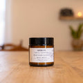 Israeli beeswax candle by Beit HaMelacha in an amber glass jar on a wooden table