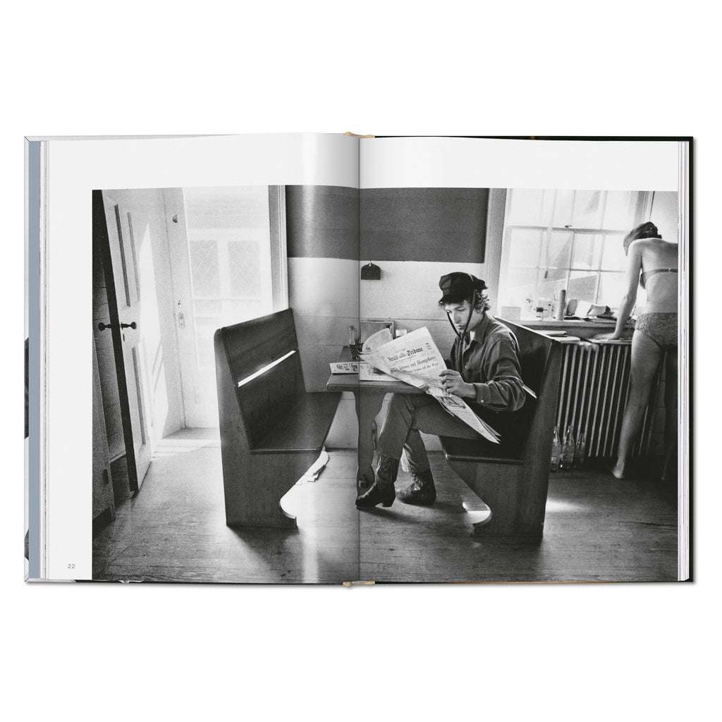 Daniel Kramer photograph of Bob Dylan sitting at a table reading a newspaper in Woodstock