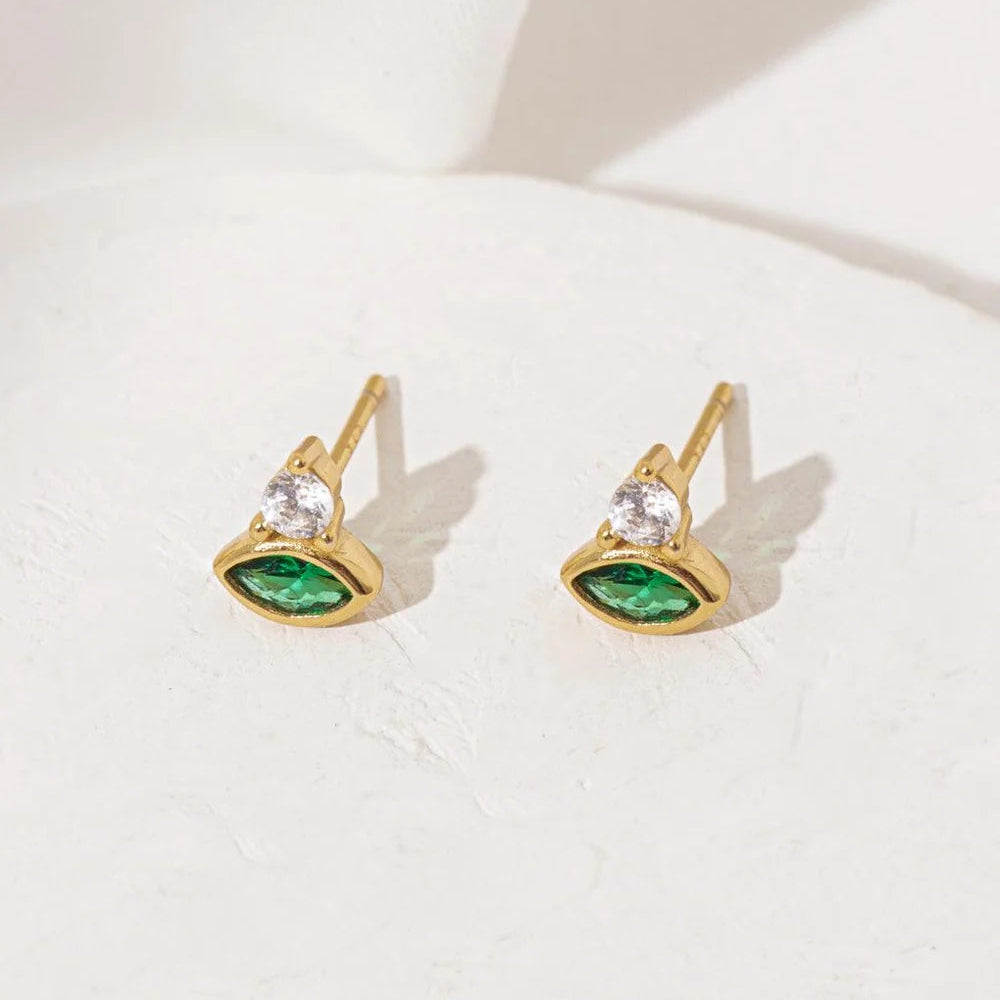 Angled view of green Cosmic Evil Eye stud earrings by Shlomit Ofir, showing the gold-tone posts and green and clear crystals.