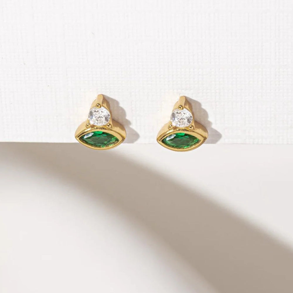 Green Cosmic Evil Eye stud earrings by Shlomit Ofir, featuring emerald-green marquise crystals and clear stones in gold-tone settings.