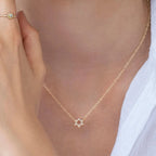 Model wearing the gold Crystal Set Star of David Necklace by Shlomit Ofir, showing the delicate crystal-studded pendant at the neckline.