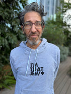 Eitan Chitayat wearing a heather gray I'm That Jew pullover hoodie with black lettering and a Star of David, photographed outdoors.