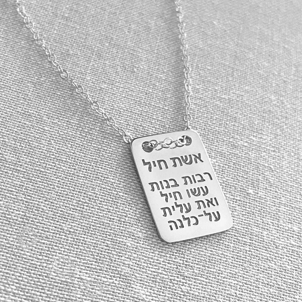 Silver necklace with a rectangular pendant on a gray fabric background