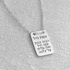 Silver necklace with a rectangular pendant on a gray fabric background