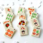 Assorted fall-themed marzipan mahjong tiles decorated with pumpkins, leaves, acorns and turkeys