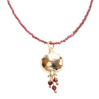 A gold plated pendant necklace with a pomegranate design, featuring red beaded chain and a gold spherical pendant.