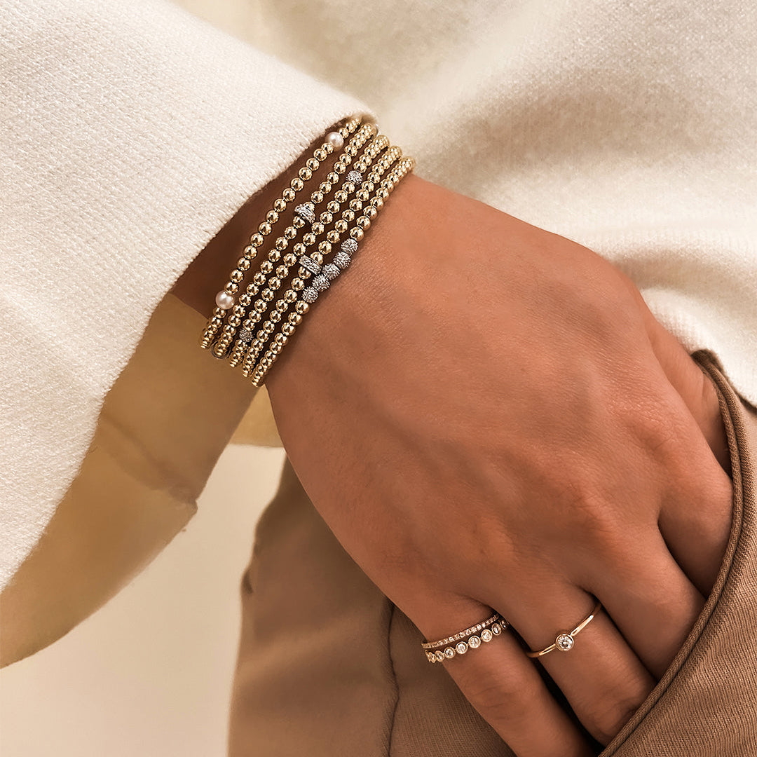 Gold and diamond bead bracelet worn in a layered bracelet stack
