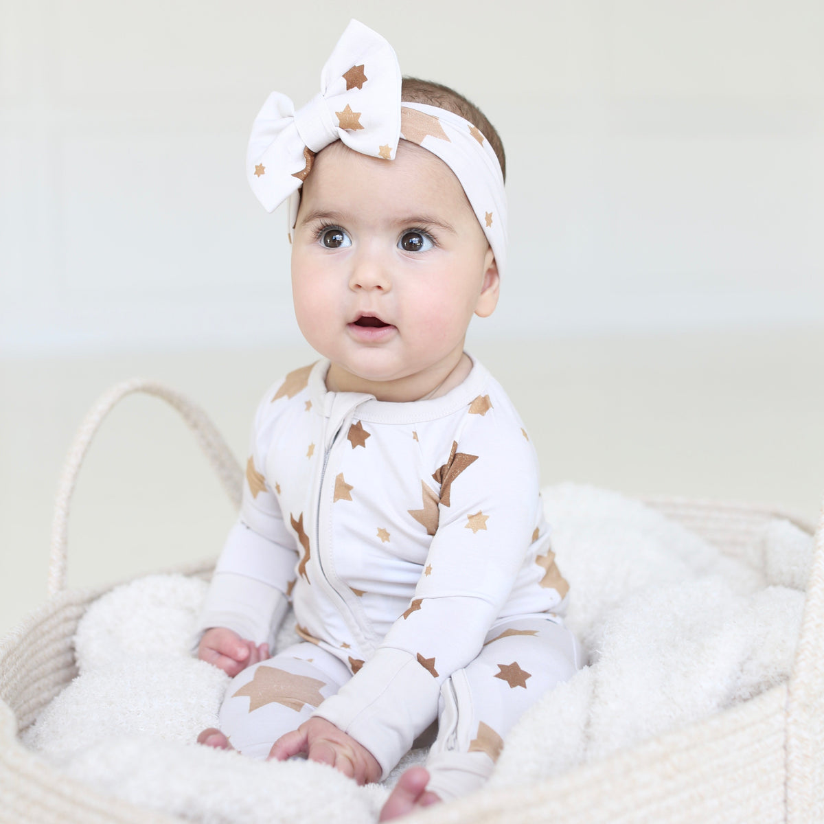 Baby wearing the Golden Hour Hanukkah bow with matching neutral Star of David pajamas.