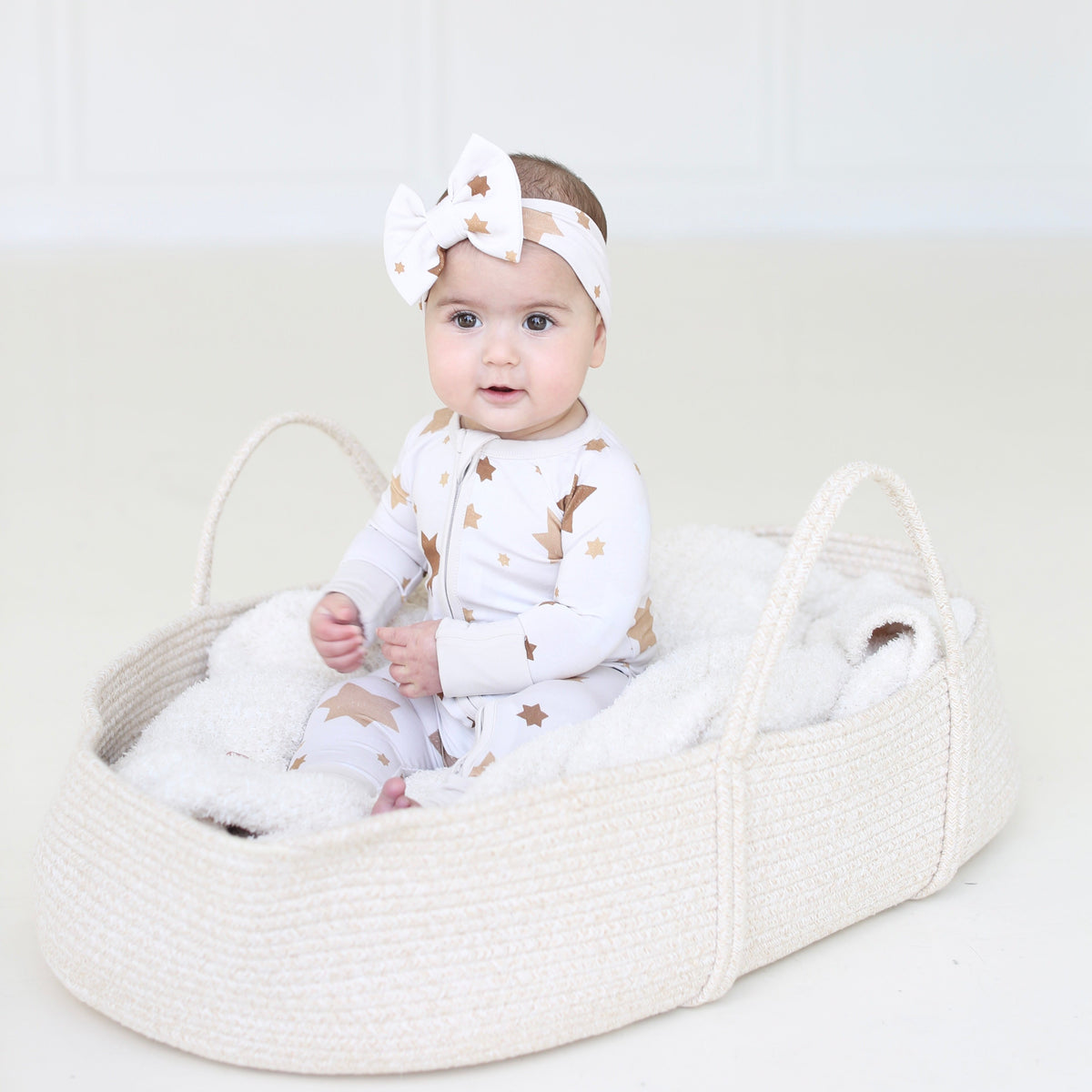 Baby wearing the Golden Hour Hanukkah bow with matching neutral Star of David pajamas.