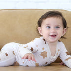 Baby wearing the Golden Hour Hanukkah Zippy with neutral gold Star of David print.