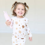 Smiling child wearing Golden Hour Hanukkah two-piece pajamas with gold Star of David print.
