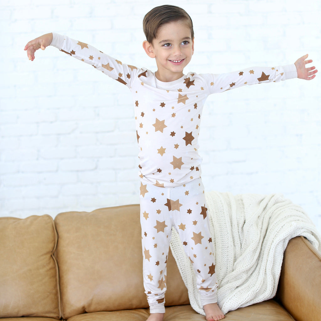Boy wearing Golden Hour Hanukkah two-piece pajamas with gold Star of David print.