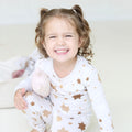 Smiling girl wearing Golden Hour Hanukkah two-piece pajamas with gold Star of David print.
