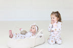 Baby and toddler wearing matching Golden Hour Hanukkah pajamas with gold Star of David print.