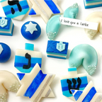 Close-up of Hanukkah marzipan treats including dreidels, Stars of David, and a fortune cookie with an “I love you a latke” message.