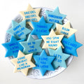 Blue, aqua, and cream Star of David marzipan conversation tiles featuring playful Hanukkah sayings arranged on a serving plate.