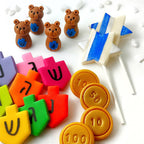 Hanukkah marzipan gift collection with colorful dreidels, gold gelt, teddy bears and blue-and-white Star of David pops.
