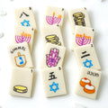 Hanukkah marzipan mahjong tiles hand-painted with menorahs, gelt, dreidels, hamsas, sufganiyot and Stars of David.