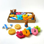 Hanukkah marzipan gift assortment with colorful dreidels, gold gelt, teddy bears and Star of David pops displayed with the gift box.