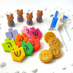 Hanukkah marzipan gift collection with colorful dreidels, gold gelt, teddy bears and blue-and-white Star of David pops.
