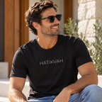 A man wears the Hatikvah short sleeve tee in vintage black, styled with jeans and sunglasses outdoors