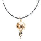 A gold plated pendant necklace with a pomegranate design, featuring hematite beaded chain and a gold spherical pendant.