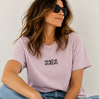 Woman wearing the Hineni mirrored graphic tee in washed lavender with jeans and sunglasses.