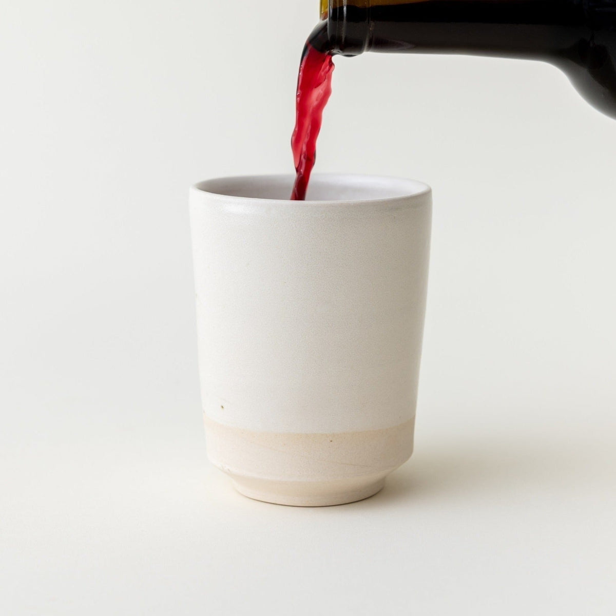 Kiddush wine being poured into a white ceramic Kiddush cup by Oneg