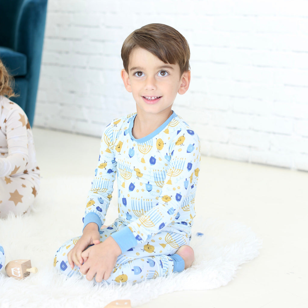 Child wearing the Latkes & Light Hanukkah two-piece set with blue and gold Hanukkah print.