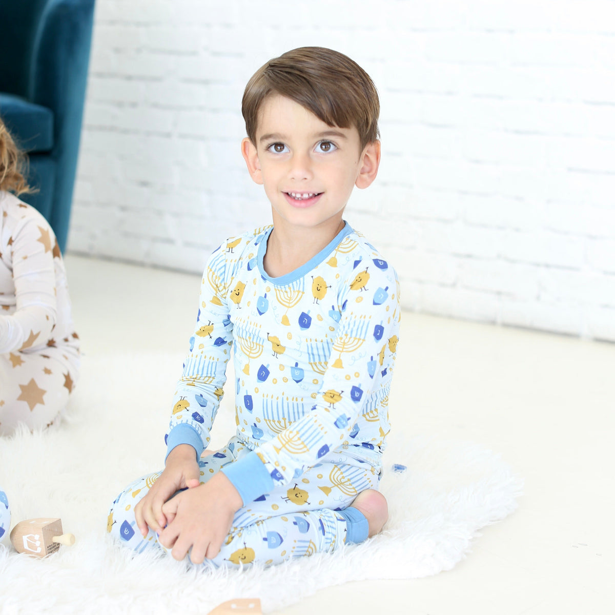 Child wearing the Latkes & Light Hanukkah two-piece set with blue and gold Hanukkah print.