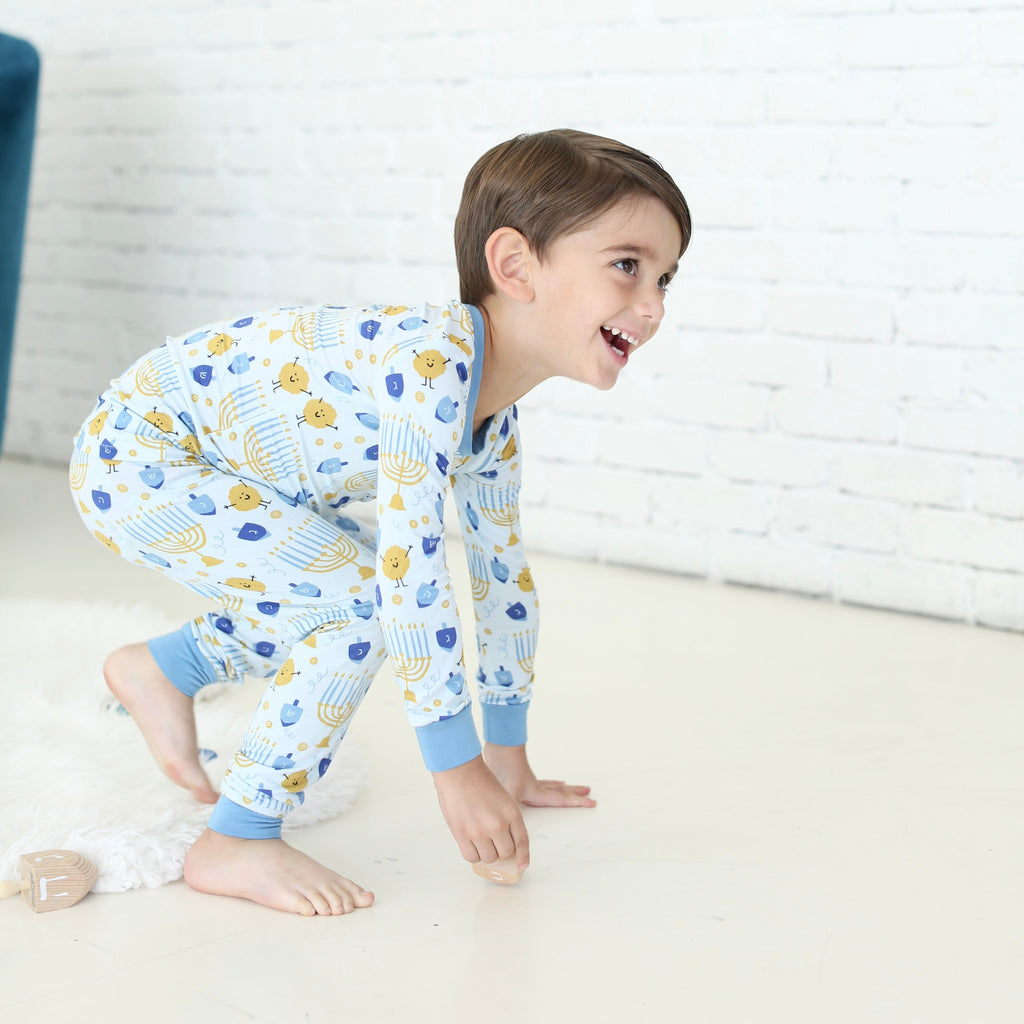 Child wearing the Latkes & Light Hanukkah two-piece set with menorah, dreidel and latke print.