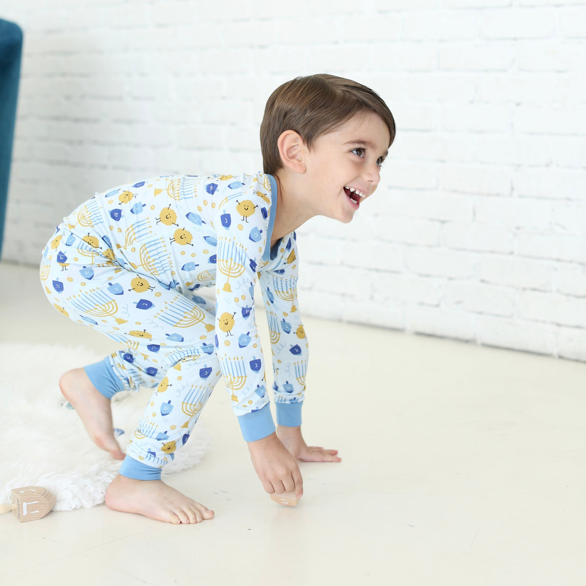 Child wearing the Latkes & Light Hanukkah two-piece set with menorah, dreidel and latke print.