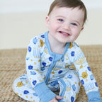 Smiling baby wearing the Latkes & Light Hanukkah Zippy with menorah, dreidel and latke print.