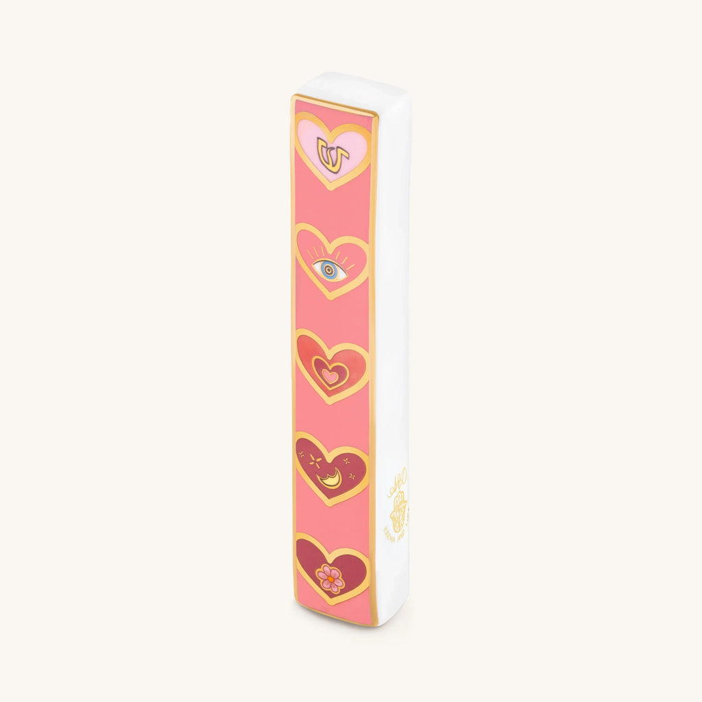 Love Lives Here ceramic heart mezuzah with pink and gold heart designs on white ceramic case