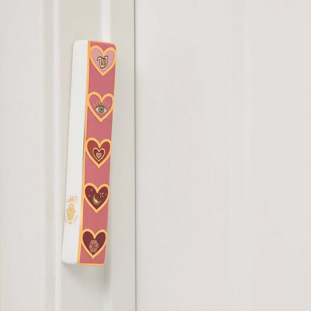 Love Lives Here pink ceramic heart mezuzah mounted on a doorframe