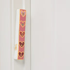 Love Lives Here pink ceramic heart mezuzah mounted on a doorframe