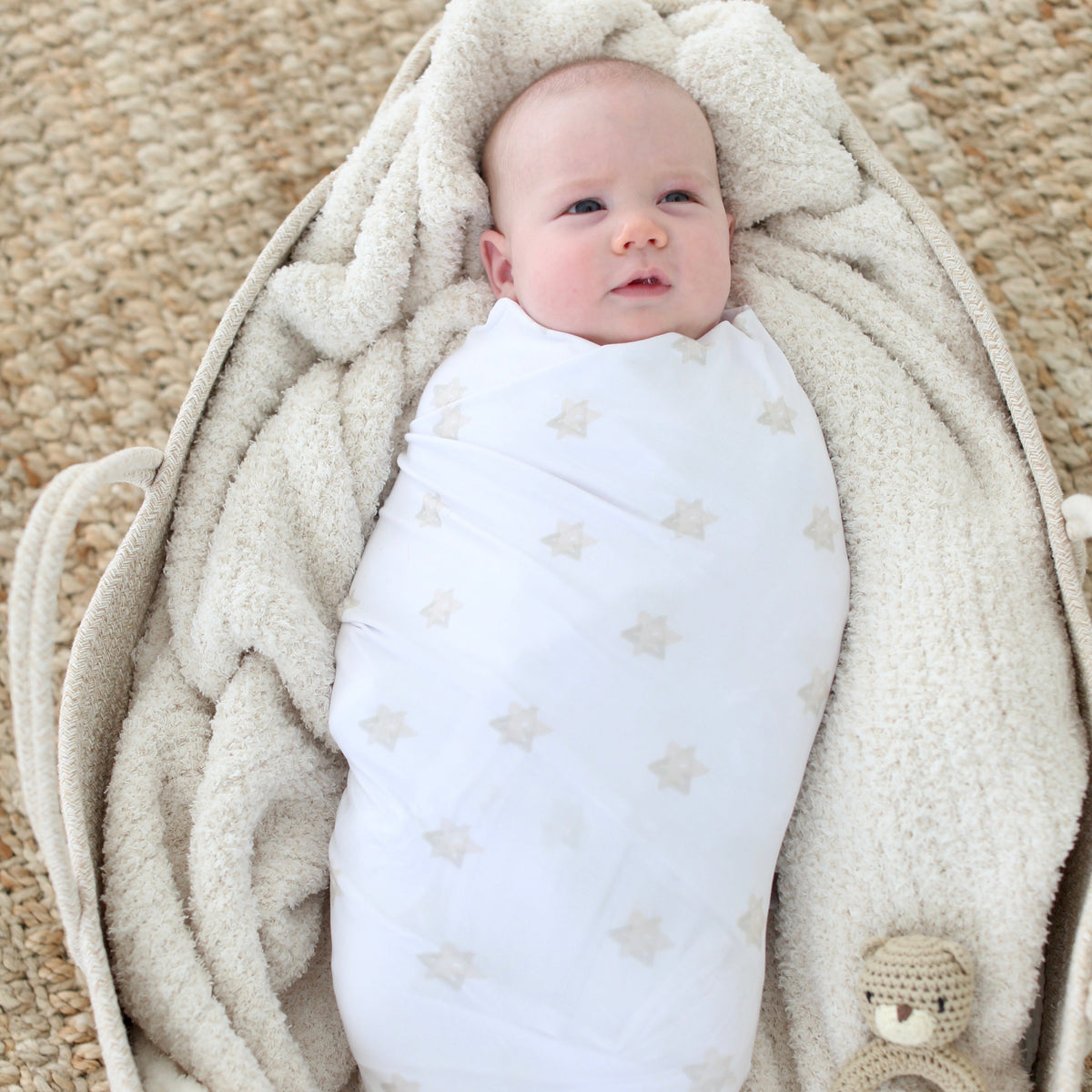 Newborn wrapped in the Magen Dreams swaddle blanket with a soft neutral Star of David print
