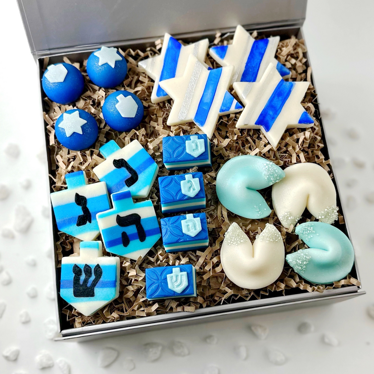 Open Hanukkah Elegant Gift Box filled with assorted blue and white marzipan dreidels, Stars of David, fortune cookies, and rainbow cookies