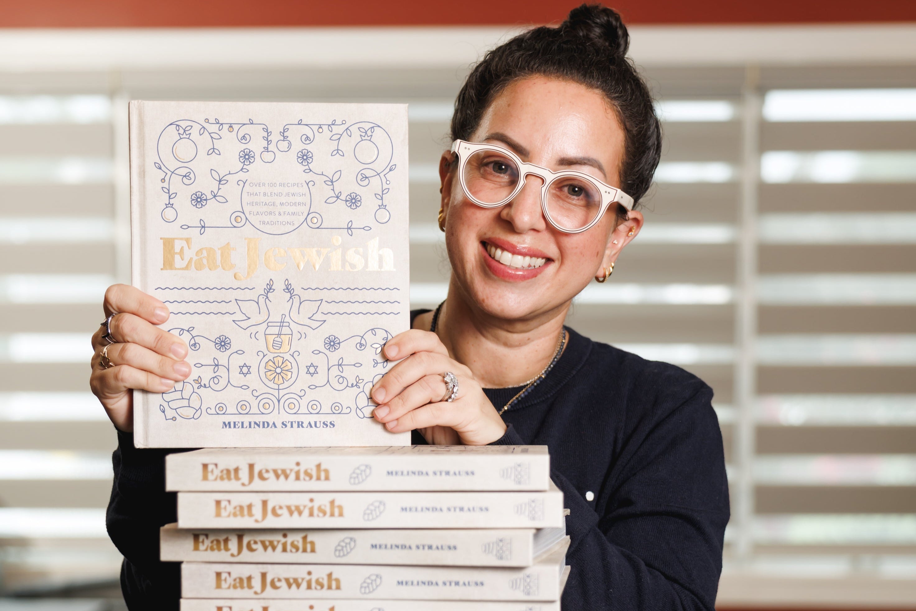 Melinda Strauss poses with a stack of "Eat Jewish" cookbooks.
