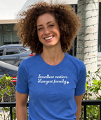 Monica Czukerberg wearing a heather blue Smallest Nation, Largest Family T-shirt with white script lettering and a Star of David, photographed outdoors.