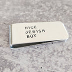 Angled view of the silver NICE JEWISH BOY money clip, showing the hand-stamped lettering and polished metal finish.