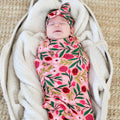 Newborn wrapped in the Petals & Pomegranates swaddle with pomegranates, florals and tiny honeybees