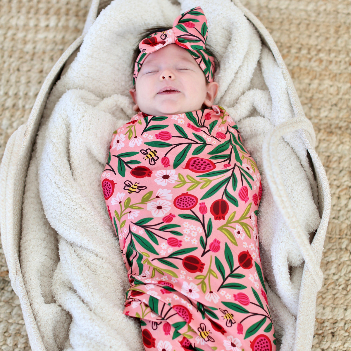Newborn wrapped in the Petals & Pomegranates swaddle with pomegranates, florals and tiny honeybees
