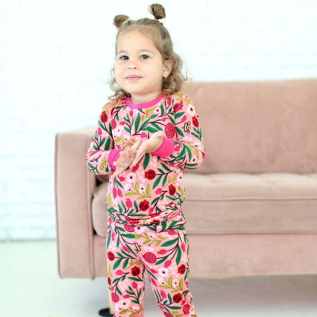 Young girl wearing the Petals & Pomegranates two-piece pajamas with pomegranates, florals and honeybees
