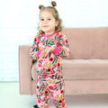 Young girl wearing the Petals & Pomegranates two-piece pajamas with pomegranates, florals and honeybees