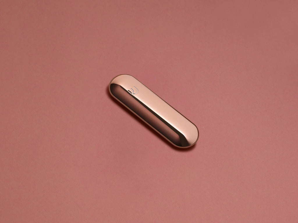 Rose Gold Pill Mezuzah shown at an angle against a blush background
